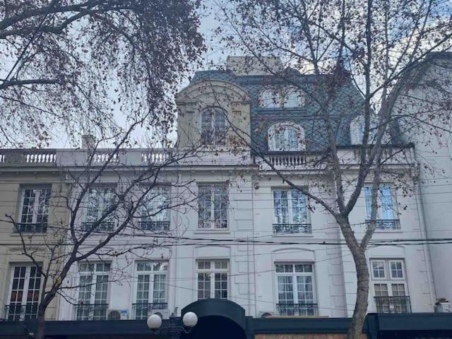 un grand bâtiment blanc avec des arbres devant lui dans l'établissement Orly Suites, à Santiago