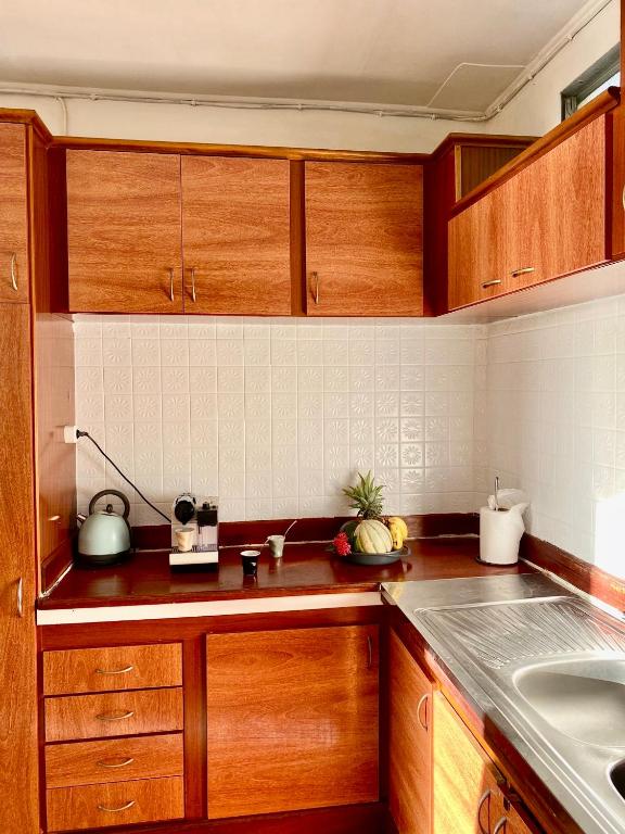 a kitchen with wooden cabinets and a sink at Télétravail et Plaisir au soleil avec vue mer! in Bouillante