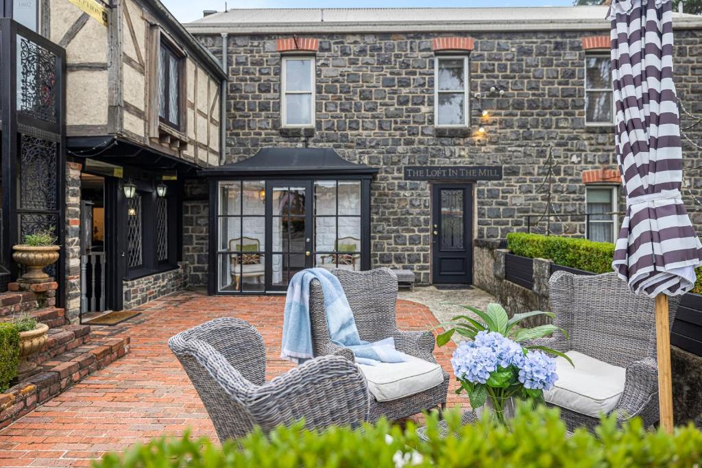 a patio with wicker chairs and a brick building at A Loft In The Mill Boutique Accommodation in Olinda