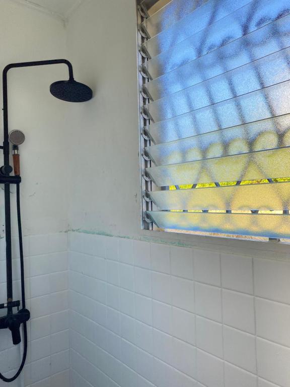a bathroom with a window and a white tiled shower at Télétravail et Plaisir au soleil avec vue mer! in Bouillante
