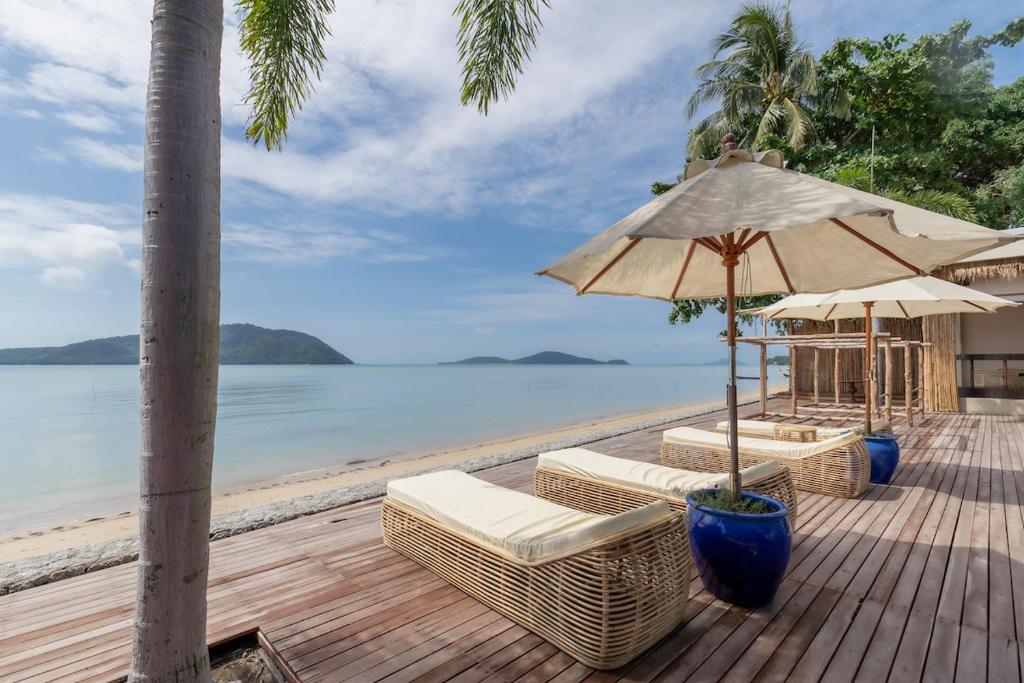 - une terrasse en bois avec des chaises et un parasol sur la plage dans l'établissement Poppy Beachfront Residence, à Rawai Beach