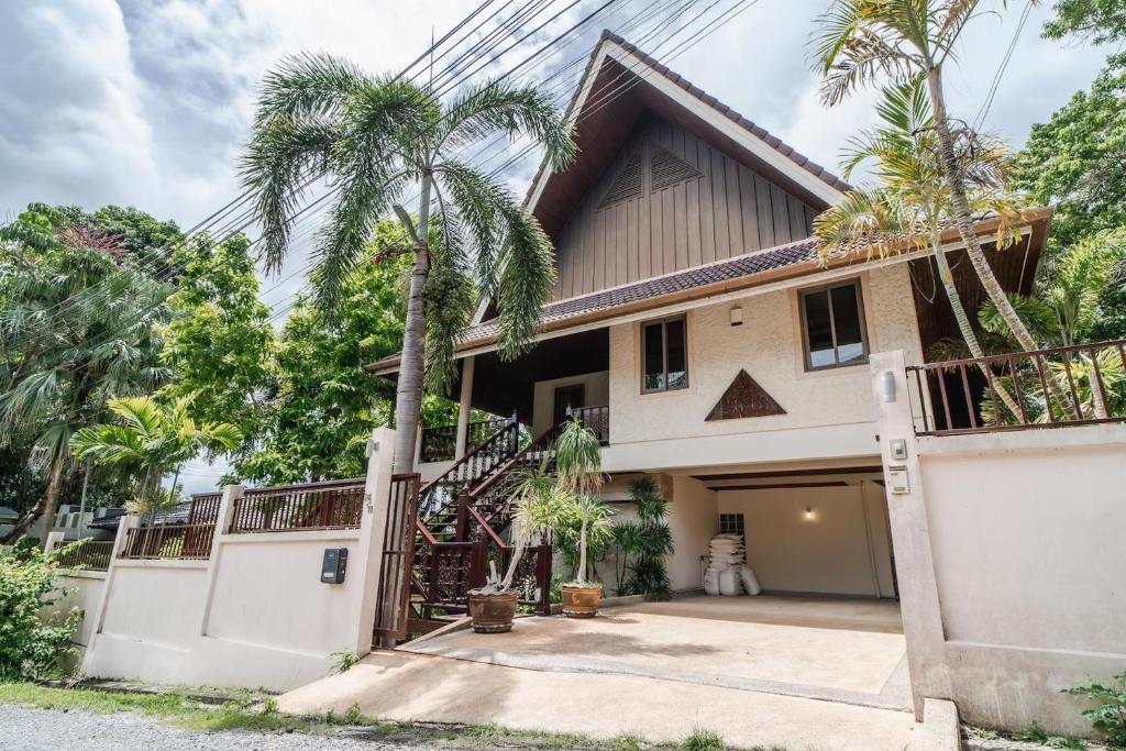 a house with a gate and palm trees at Orchid Pool Villa in Rawai in Rawai Beach