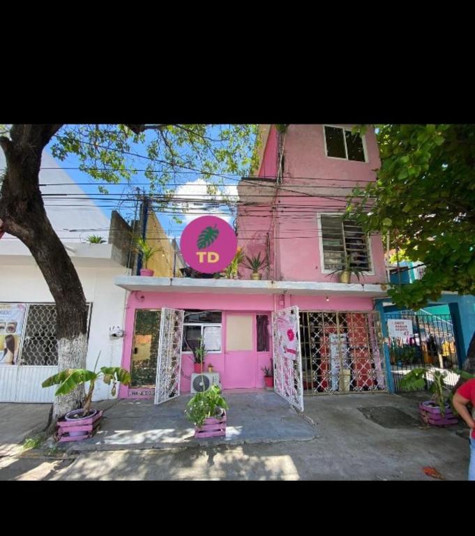 un edificio rosa con un cartel. en Tropical Dreams en Villahermosa