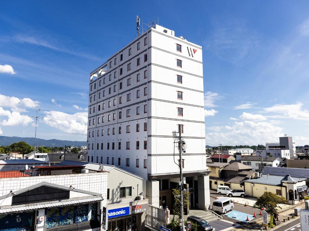 Hotel Wing International Sukagawa في Sukagawa: مبنى ابيض عليه برج الساعه