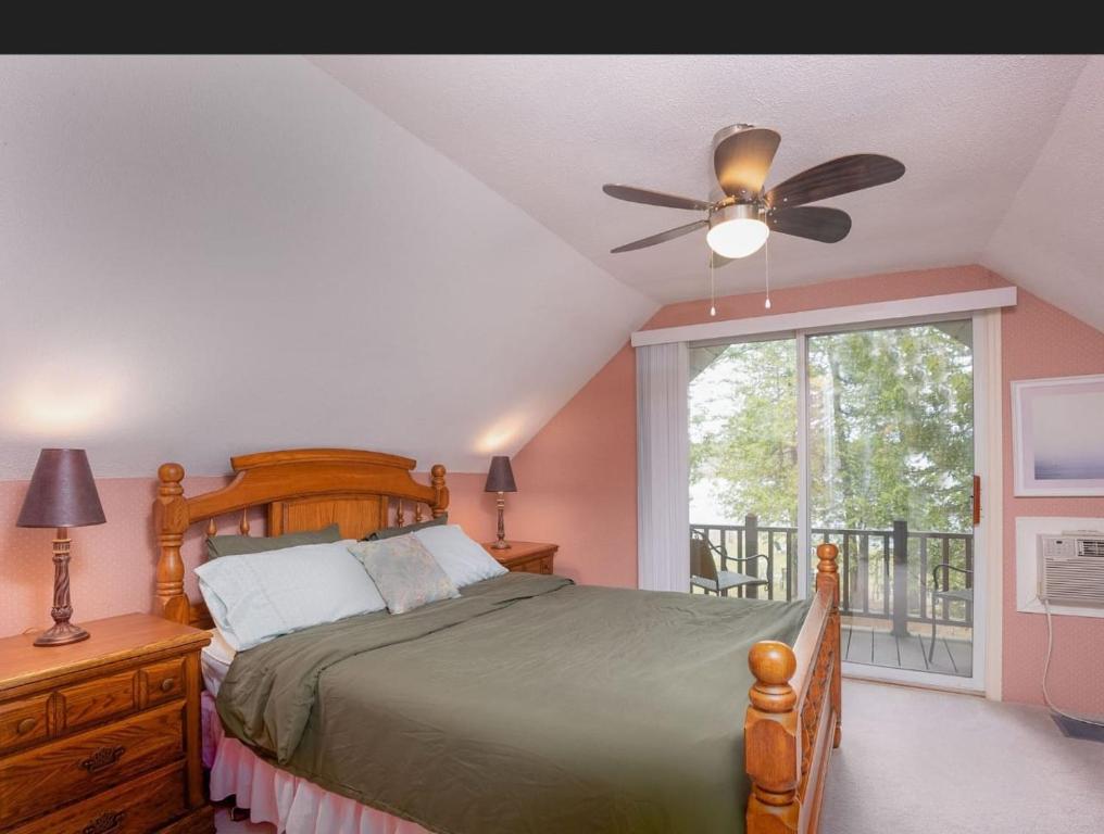 - une chambre avec un lit, un ventilateur de plafond et une fenêtre dans l'établissement Lovely waterfront private cottage with hot tube, à Head Lake