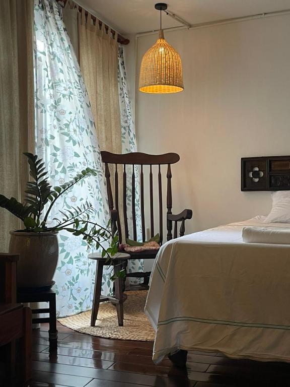 a bedroom with a bed and a chair and a potted plant at Mận Đào Villa in Ho Chi Minh City