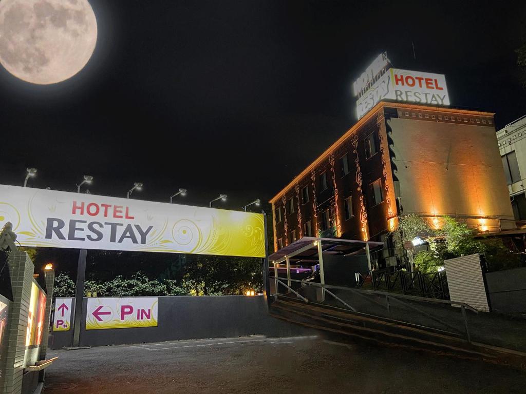 a hotel at night with a full moon in the sky at Restay Tokorozawa (Adult Only) in Tokorozawa