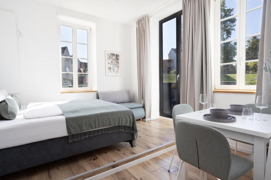 een slaapkamer met een bed, een bureau en ramen bij DWELLSTAY - Zuse Höfe Bad Hersfeld in Bad Hersfeld