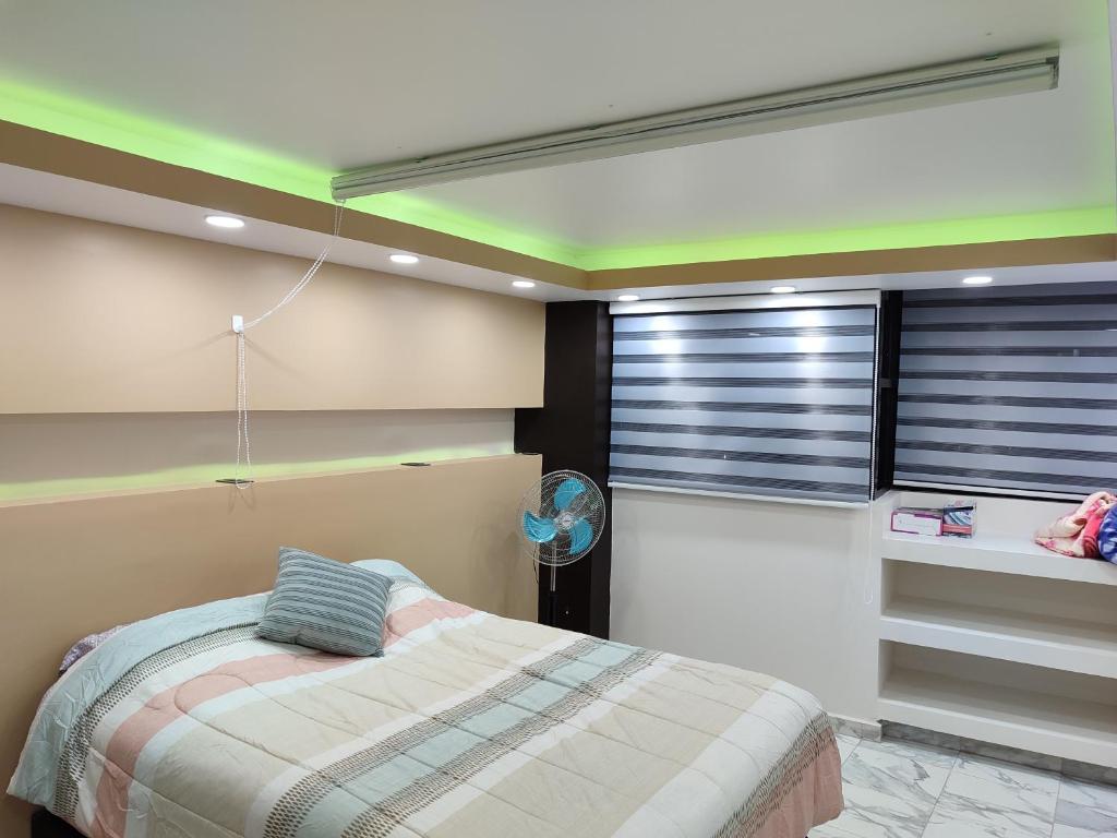 ein Schlafzimmer mit einem Bett und einer grünen Decke in der Unterkunft Departamento ejecutivo de lujo in Atlacomulco de Fabela