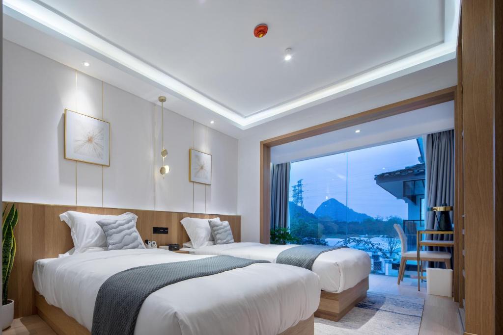 two beds in a room with a large window at Guilin Bonjour Boutique Hotel in Guilin