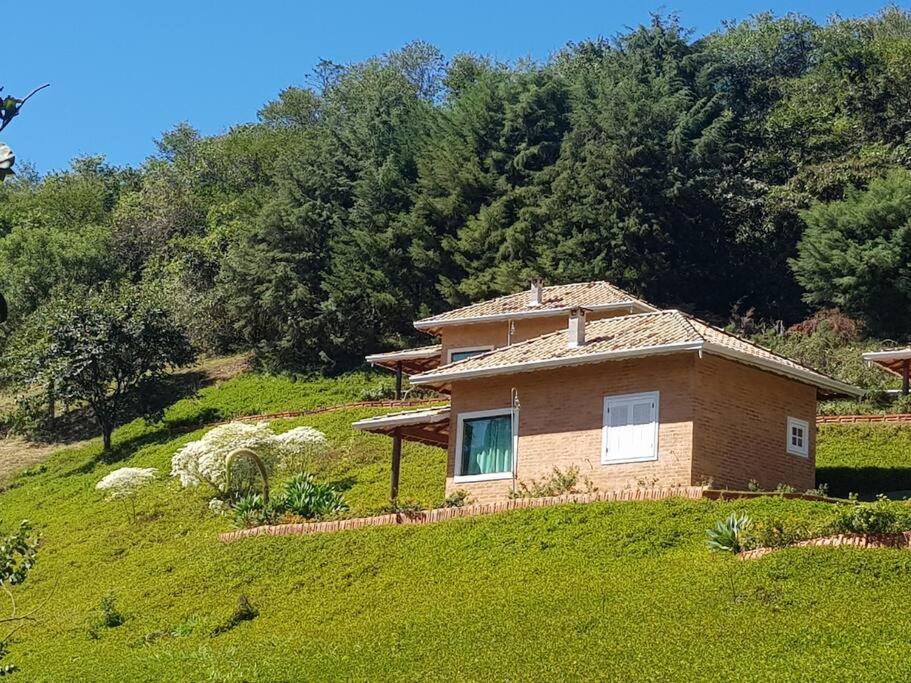 ein kleines Backsteinhaus auf einem grasbewachsenen Hügel in der Unterkunft Recanto dos Beija flores, Chalé lantana b in Monte Alegre do Sul