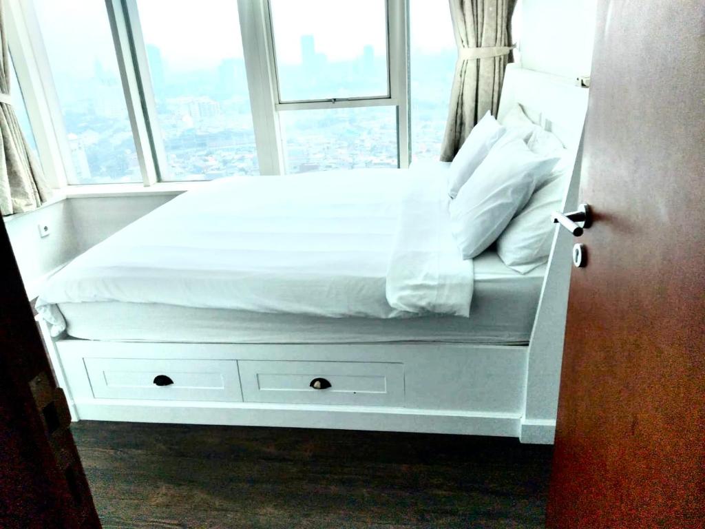 - un lit blanc dans une chambre avec fenêtre dans l'établissement Thamrin Residences/2BR, à Jakarta