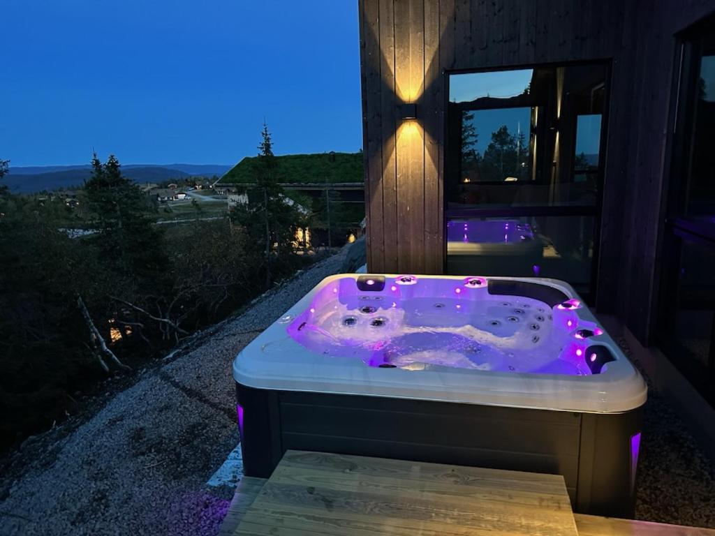 Stylish cabin at Lifjell with jacuzzi and sauna في بوه: حوض جاكوزي مع أضواء أرجوانية أمام المنزل