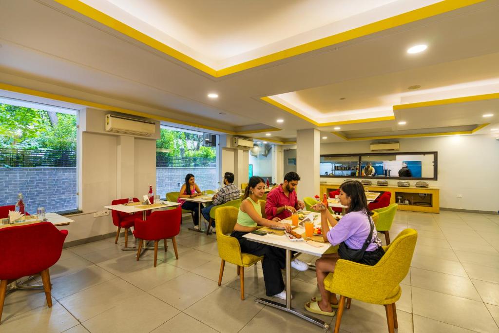 un grupo de personas sentadas en mesas en un restaurante en The Hosteller Gurugram en Gurgaon