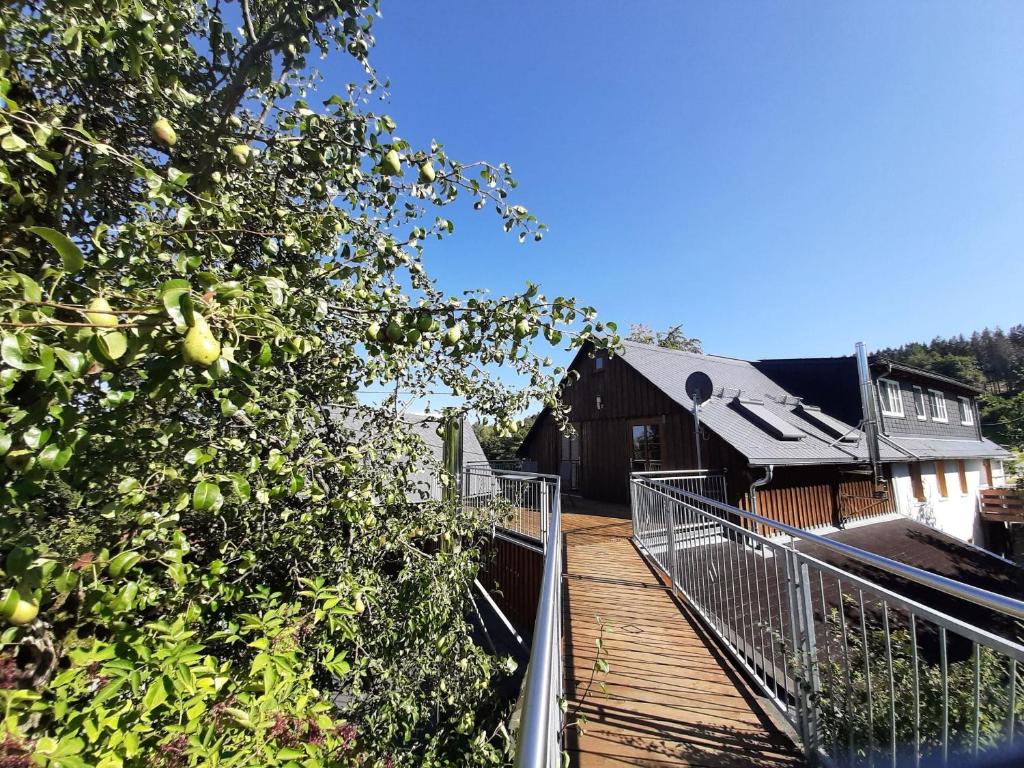 eine Holzterrasse mit einem Baum und einem Gebäude in der Unterkunft Ferienwohnung Hägelhof in Naila