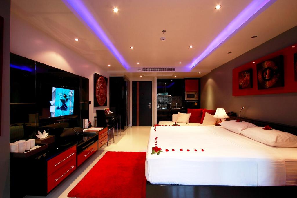a bedroom with a large white bed and a television at Absolute Bangla Suites in Patong Beach