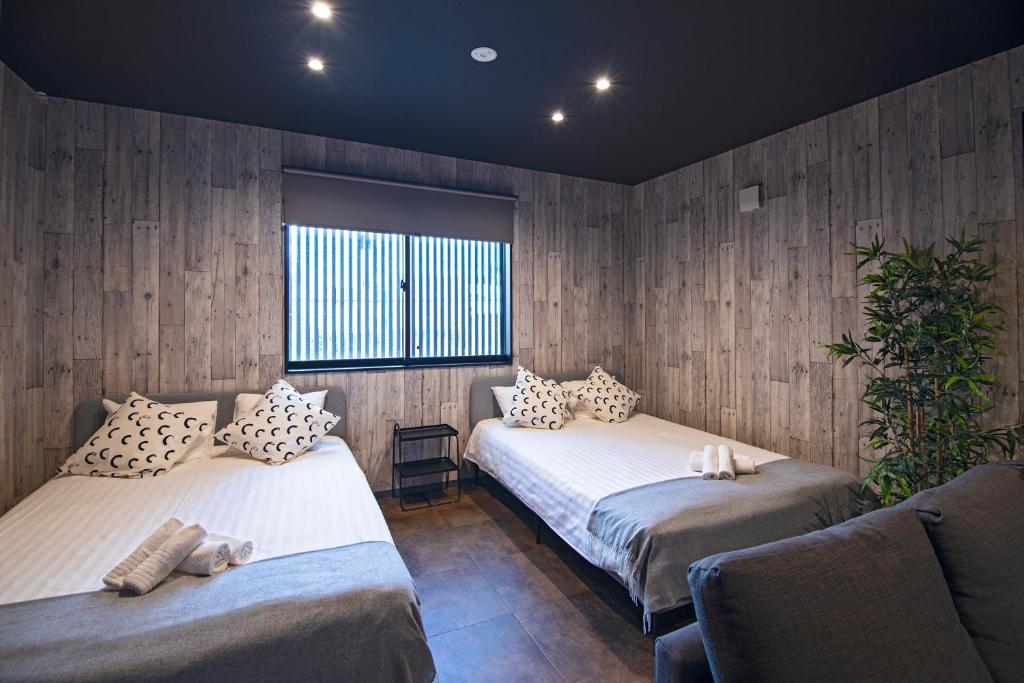 twee bedden in een kamer met houten wanden bij Time通天閣2F 近隣Tsutenkaku Nihonbashi in Osaka