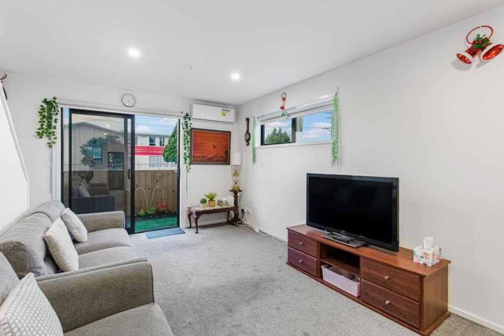 a living room with a couch and a flat screen tv at Stunning 2BR in Kelston - WIFI - Carpark in Auckland