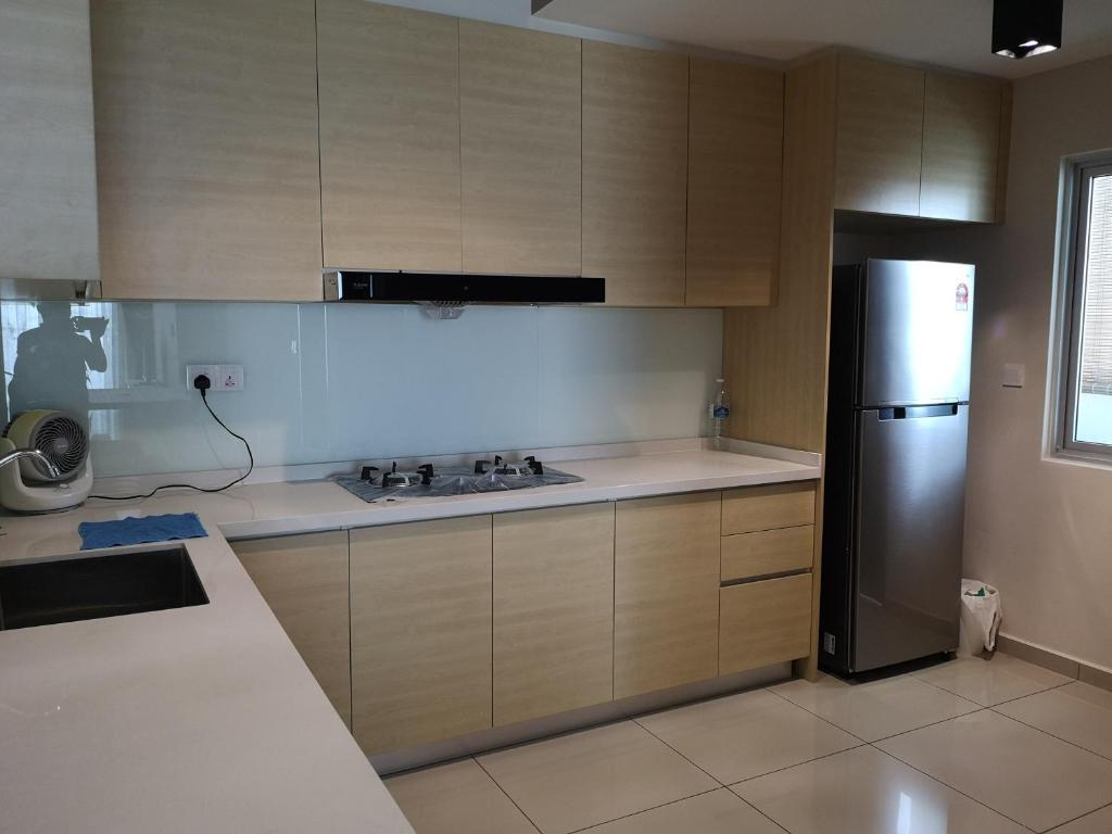 a kitchen with wooden cabinets and a stainless steel refrigerator at Metropol Suite in Bukit Mertajam