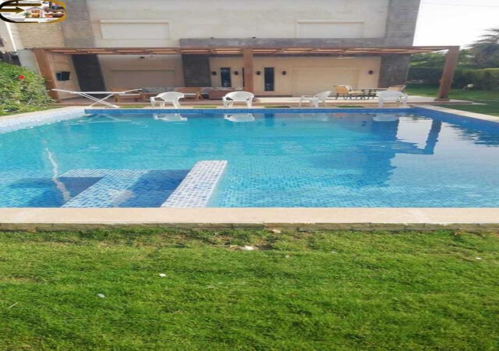 a large swimming pool with blue water in a yard at من افخم الشاليهات في الساحل شمالي برايفت بول مارينا in El Alamein