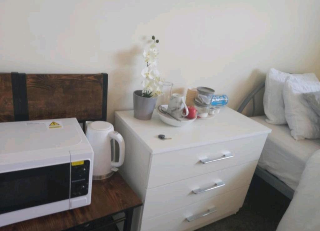 einen kleinen Tisch mit einer Mikrowelle und einem Bett in der Unterkunft Fresher Space Home Stay in Walsall