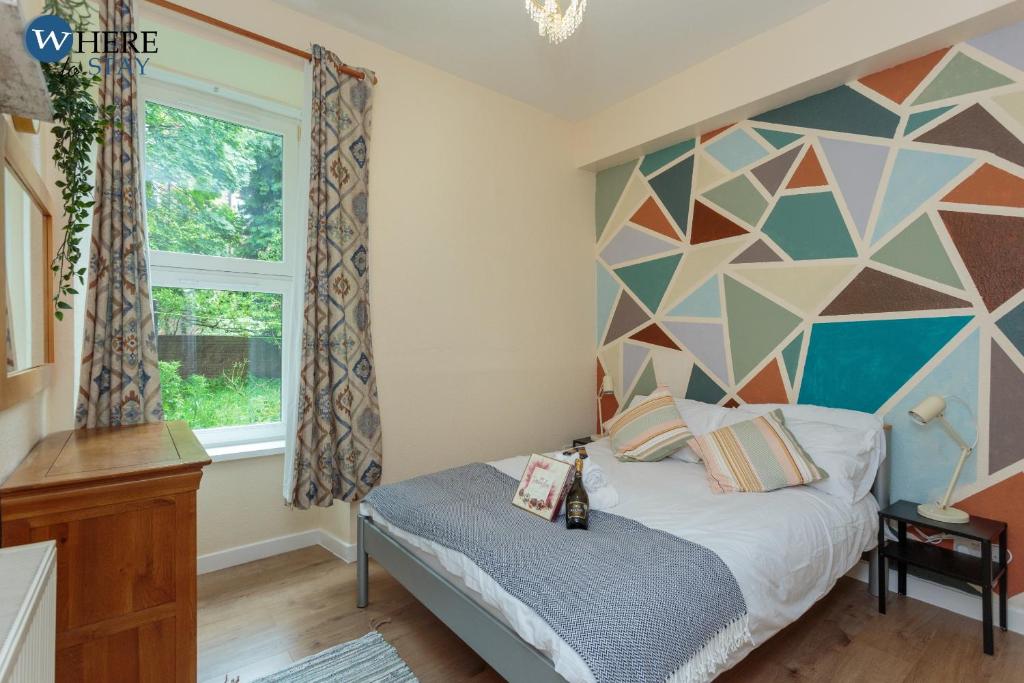 a bedroom with a bed with a geometric wall at Cosy 1 bed flat near city centre in Edinburgh