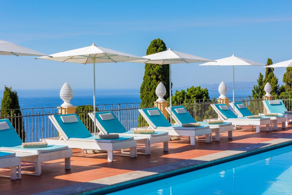 - une rangée de chaises et de parasols à côté de la piscine dans l'établissement Grand Hotel San Pietro, à Taormine