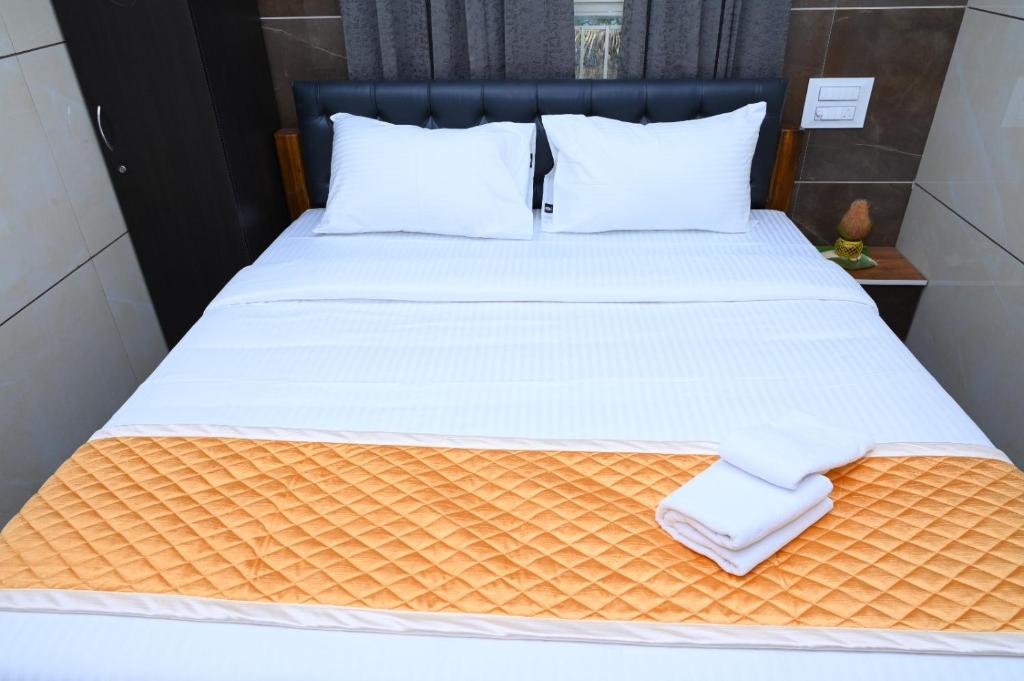 een bed met witte lakens en kussens erop bij ESHANNA RESIDENCY in Davangere