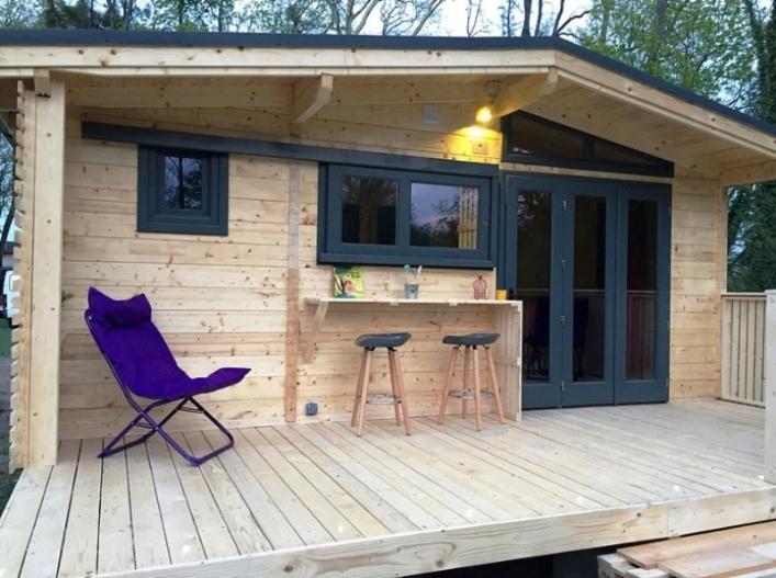 a cabin with a purple chair and a bar on a deck at chalet nature sur la vallée de la Truyère in Neuvéglise