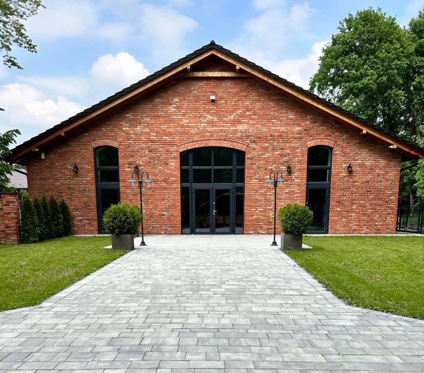 un edificio de ladrillo rojo con una puerta grande en Red Barn en Spała