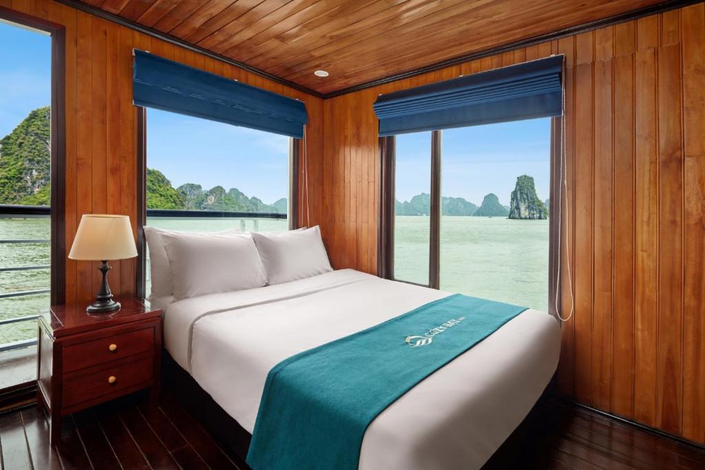 a bedroom with a bed and windows in a boat at Cozy Bay Cruise in Ha Long
