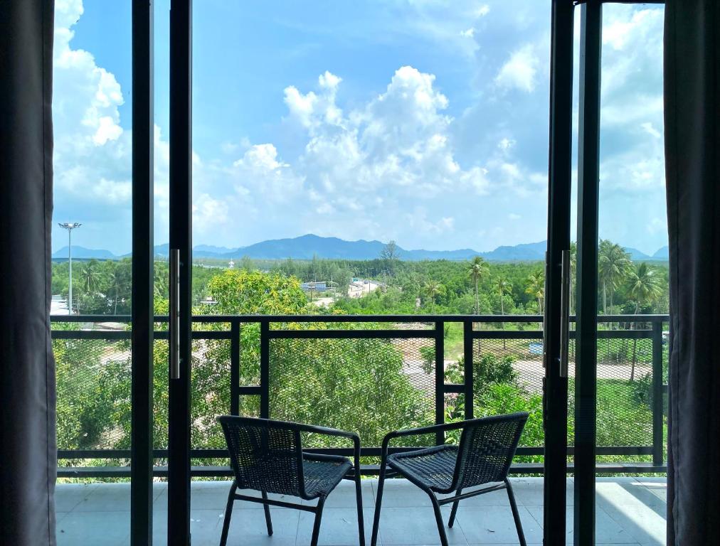 two chairs on a balcony with a view of the mountains at De Saran Lanta in Ko Lanta