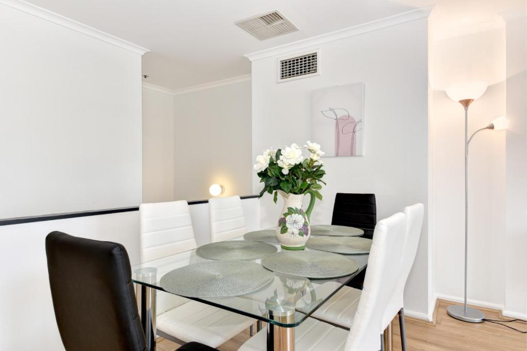 a dining room with a glass table and white chairs at Beautiful apartment in Pyrmont in Sydney