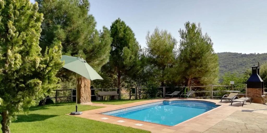 una piscina en un patio con sombrilla en Caso Nou, en La Baronia de Rialb