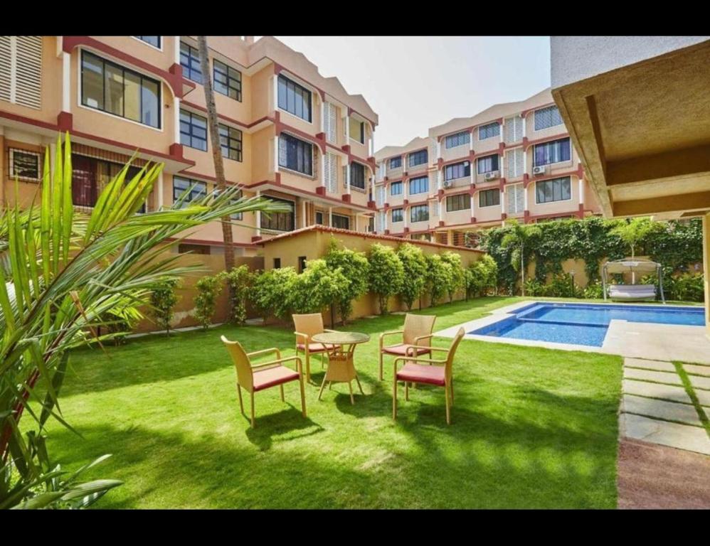 un patio con mesa, sillas y piscina en Veeraas Calangute - 2BHK Apartment with Pool en Marmagao
