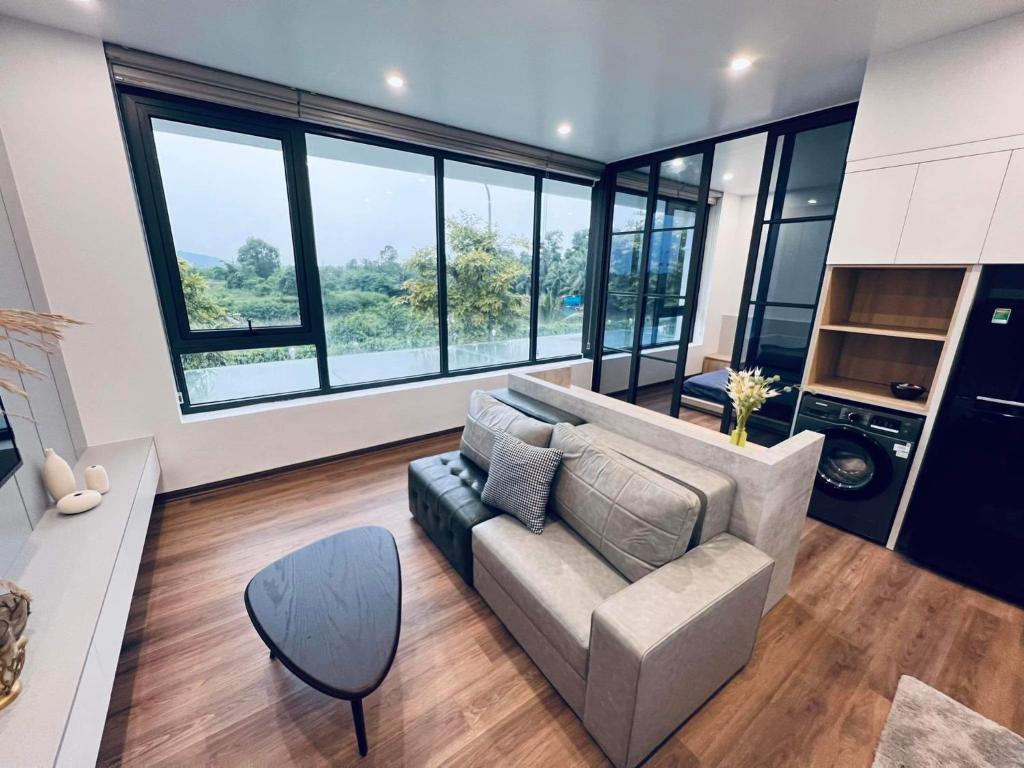 a living room with a couch and some windows at MinA Apartment - Vinhome Marina Hải Phòng in Hai Phong