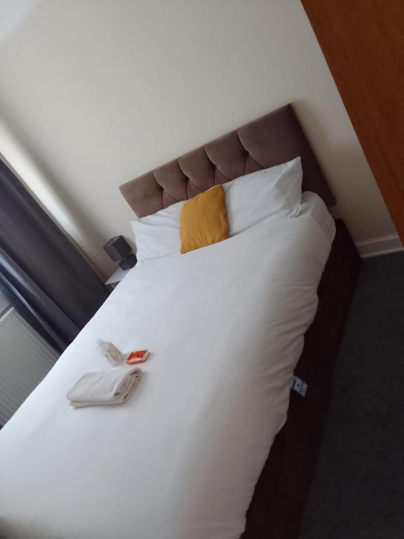 a large white bed with a yellow pillow on it at Mide’s House in Invergowrie