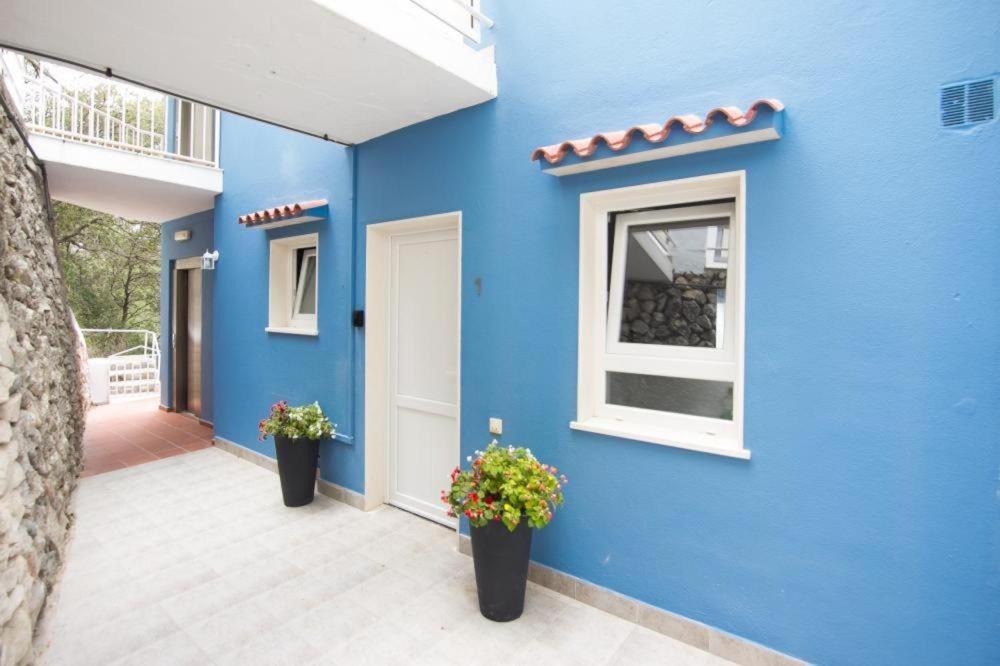 un edificio azul con dos macetas en un patio en Cala Galdana Apartamentos El Rio, en Cala Galdana