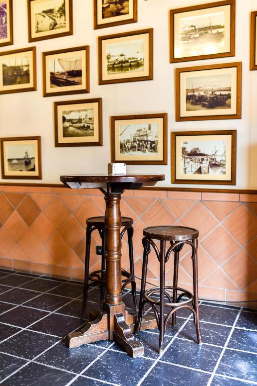 a table and two stools in a room with pictures on the wall at ALEGRIA Bodega Real in El Puerto de Santa María