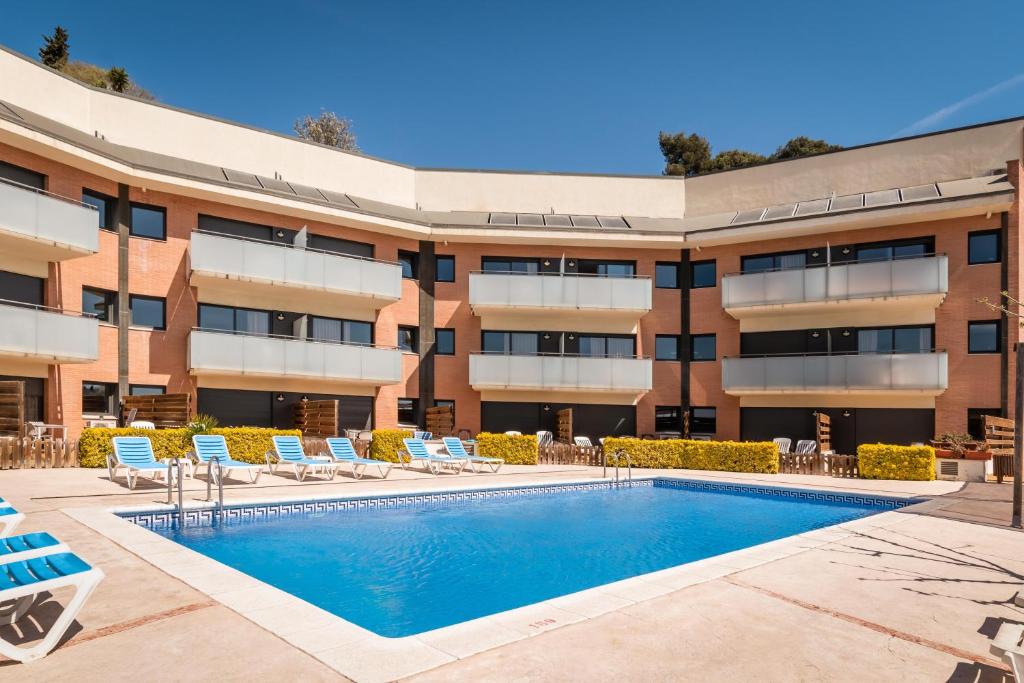 聖蘇珊娜的住宿－SANTA SUSANNA Chic! Apartments by ALEGRIA，享有带游泳池和椅子的建筑的外部景色