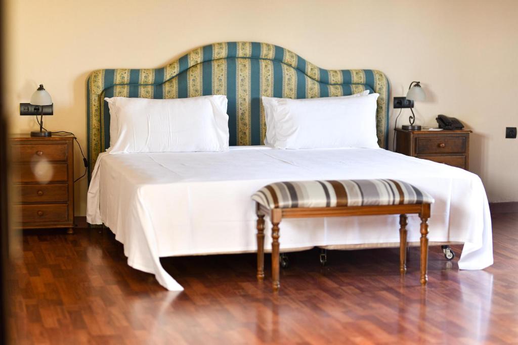 a bedroom with a large white bed with a green headboard at ALEGRIA Bodega Real in El Puerto de Santa María