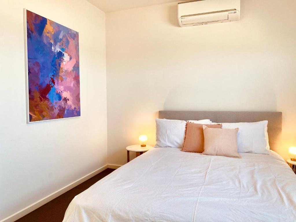 a bedroom with a white bed with a painting on the wall at 2B house with private entry free parking 4mins to Airport in Melbourne