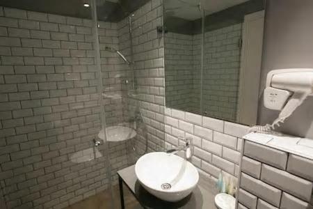 a bathroom with a glass shower and a sink at City Port Hotel in Haifa