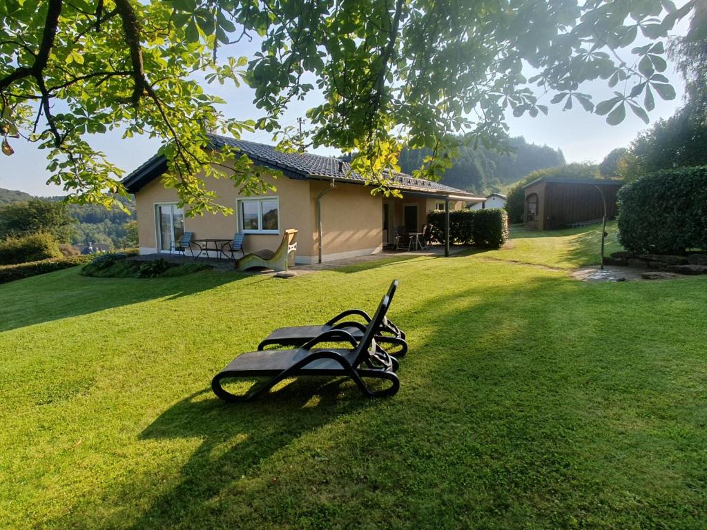 un banco sentado en el césped frente a una casa en Ferienhaus "et Eifelparadiesje", en Gerolstein