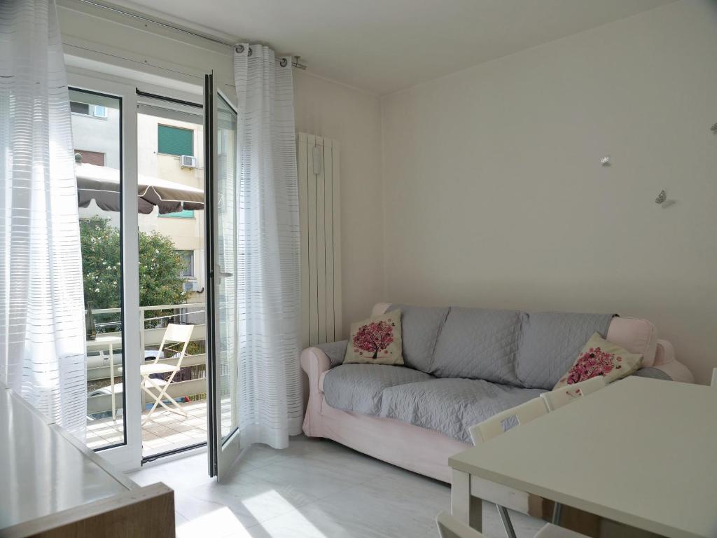 格拉多FIORE DI MARE - Delizioso bilocale con posto auto vicino al porto的带沙发和阳台的客厅