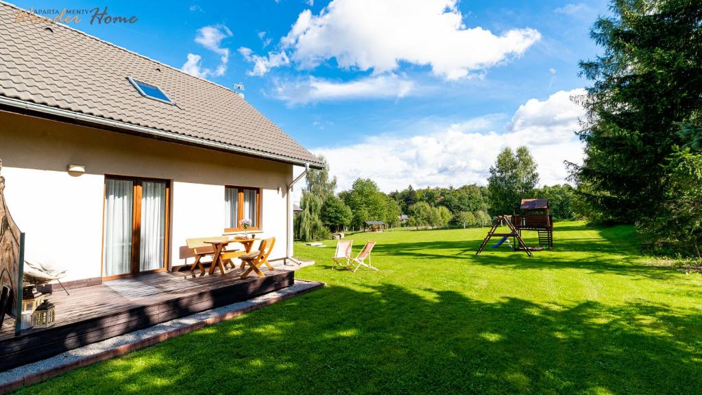 una casa con terraza de madera junto a un patio en Wonder Home - Apartamenty Czerwony Dworek - duży teren zielony, plac zabaw, miejsce na grilla i staw z możliwością wędkowania, en Mysłakowice