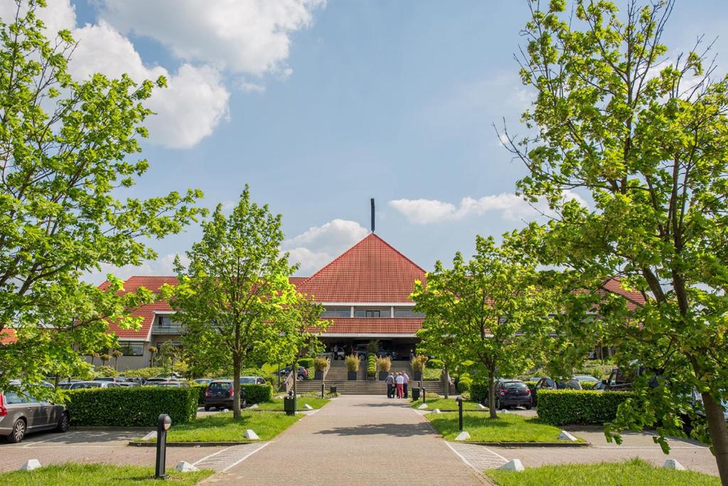 un edificio con techo rojo y aparcamiento en Van der Valk Hotel Hengelo, en Hengelo