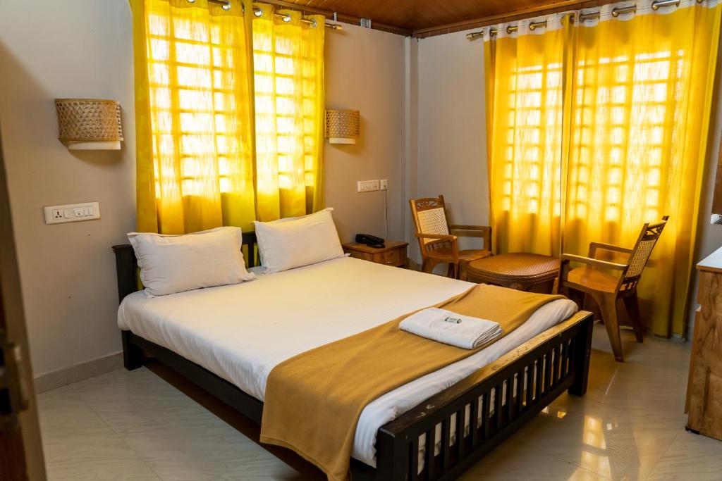 a bedroom with a large bed with yellow curtains at DREAMS AIRPORT RESIDENCY in Nedumbassery