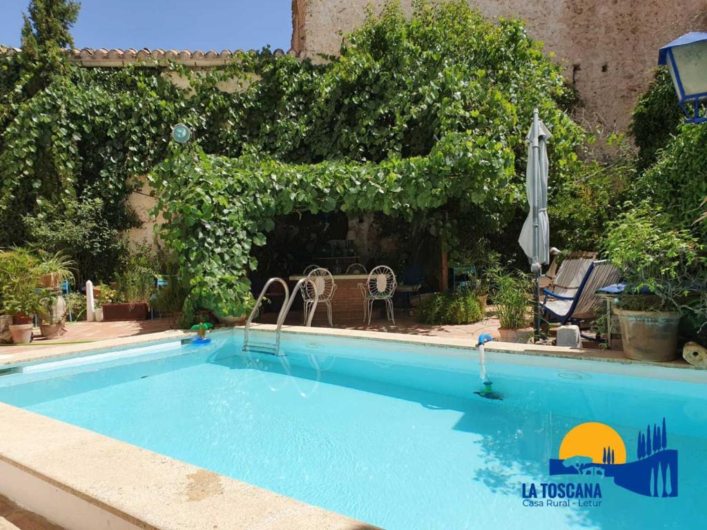 a swimming pool in a yard with an umbrella at La Toscana de Letur in Letur