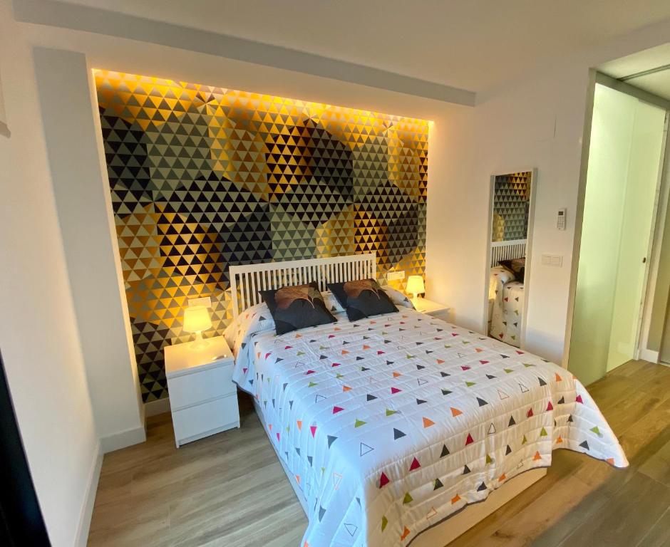 Un dormitorio con una cama grande y una pared de botellas de vino en AIRVA: Apartamentos Bajada de la Libertad, en Valladolid